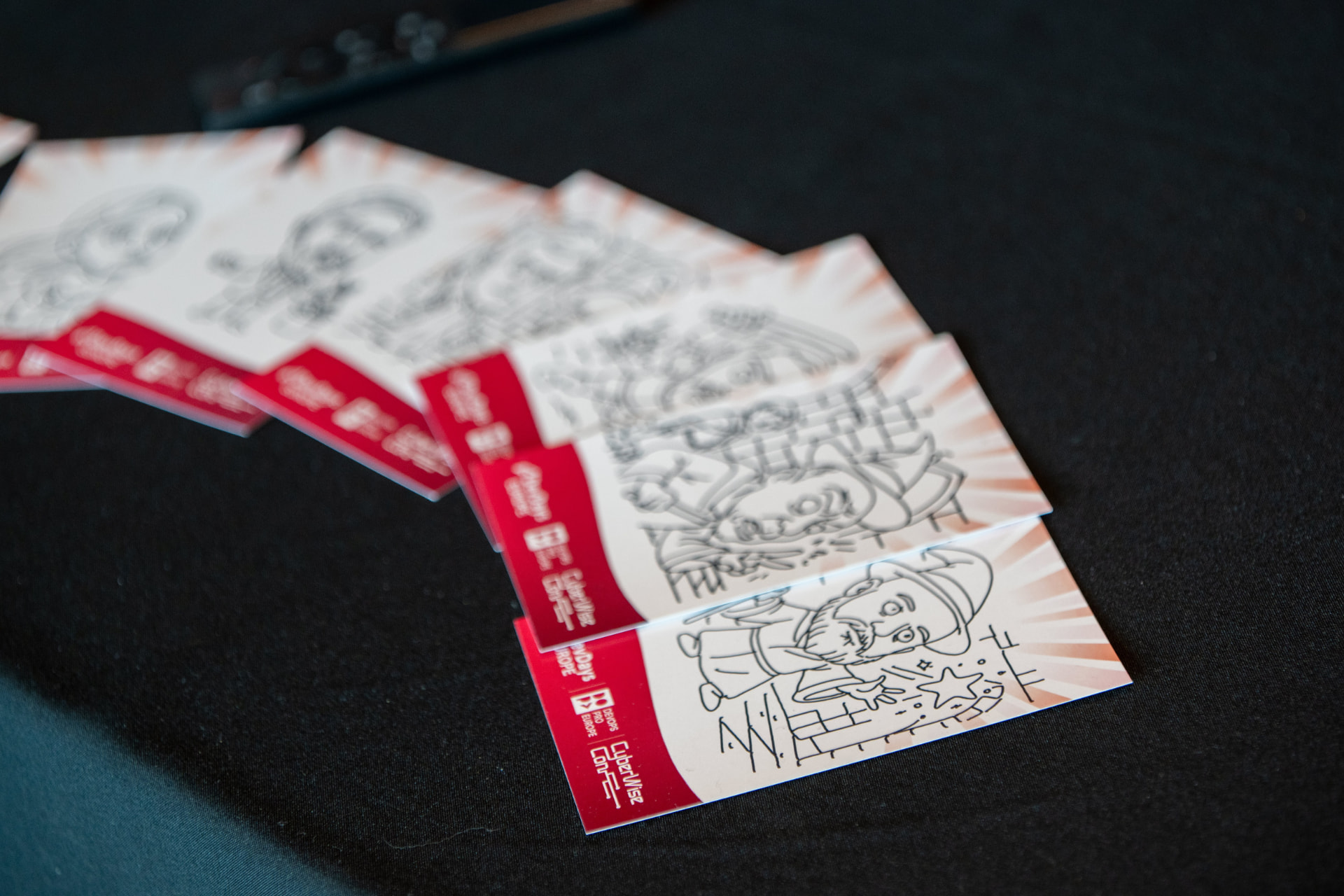 A fan of branded cards with robot-drawn portraits of event guests